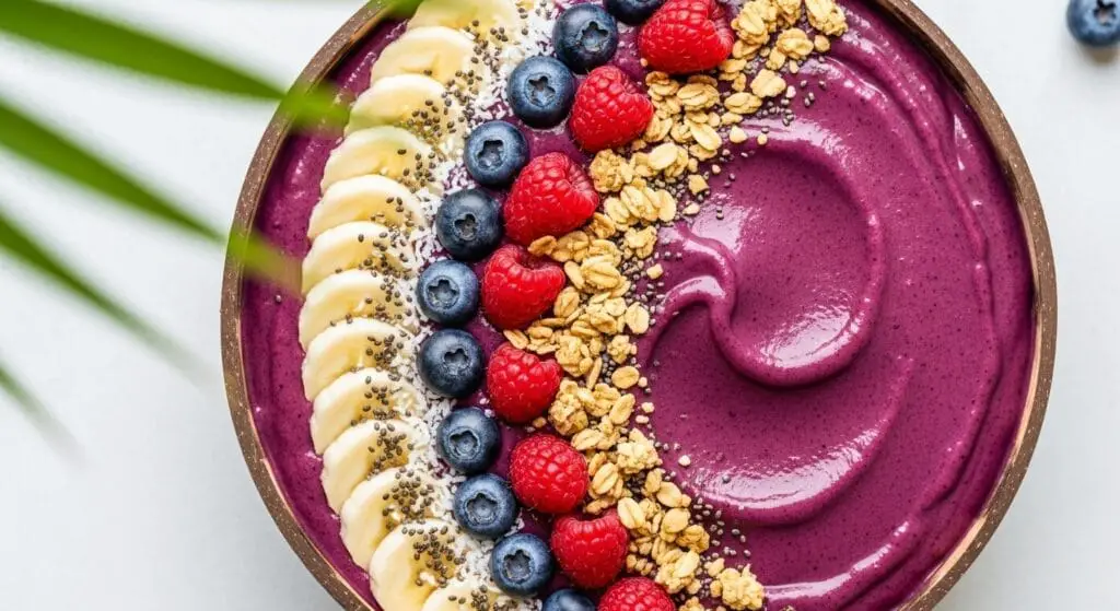 Stunning hero shot of a vibrant, deep purple Acai Coconut Smoothie Bowl in a stylish bowl, artfully topped with sliced banana, fresh berries (blueberries, raspberries), granola, shredded coconut, and perhaps a drizzle of honey or nut butter.