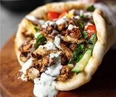 Plate of Chicken Shawarma served with garlic sauce and fresh vegetables
