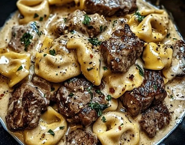 Cracked garlic steak tortellini in creamy sauce served in a bowl.