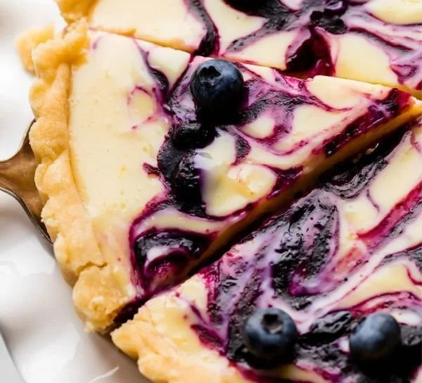 Creamy lemon tart with blueberry sauce served on a plate
