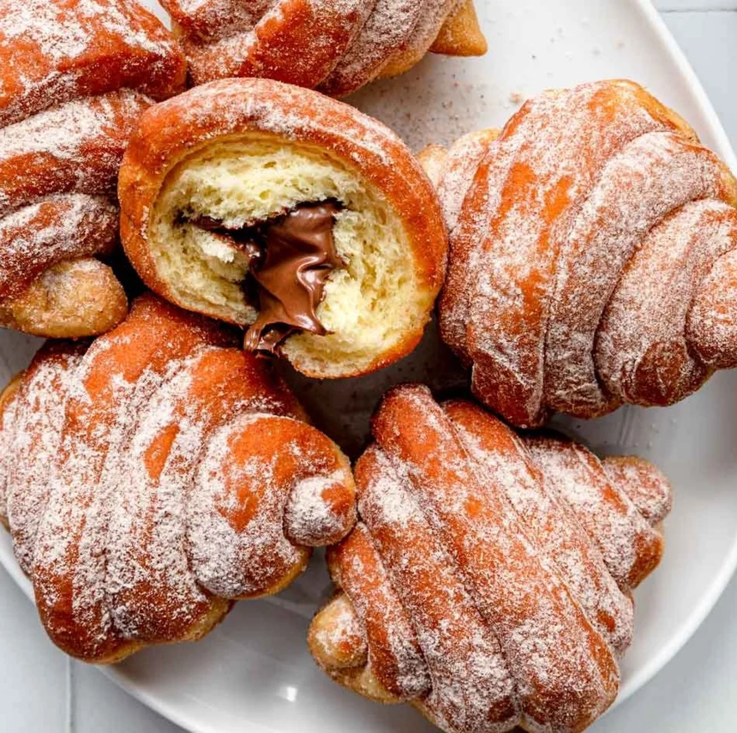 Fried croissant beignets dusted with powdered sugar