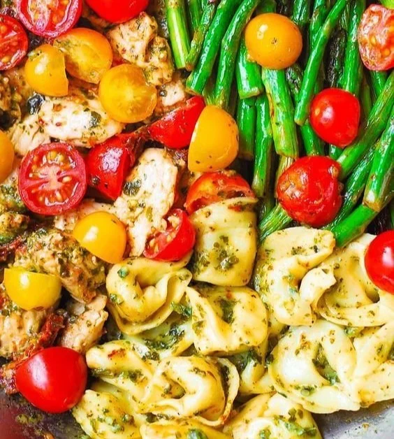 One-pan pesto chicken with tortellini and mixed vegetables in a skillet