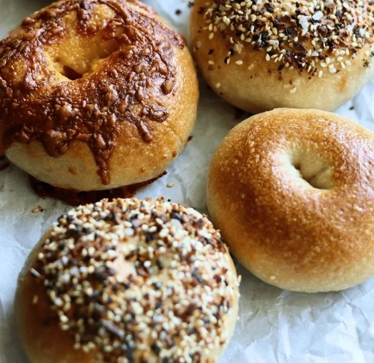 Homemade sourdough bagels resting on a wooden board
