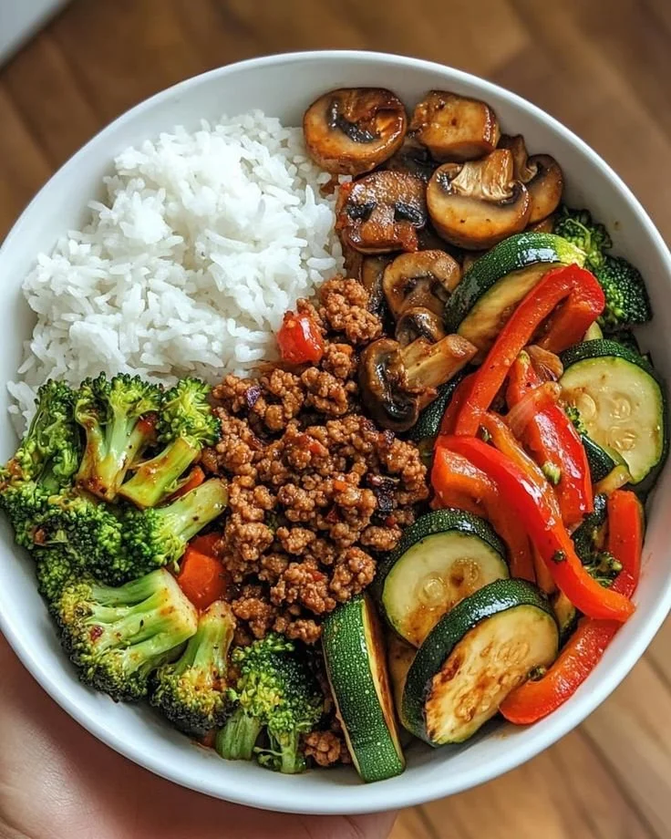 Spicy ground beef stir-fry bowl with garlic vegetables and rice