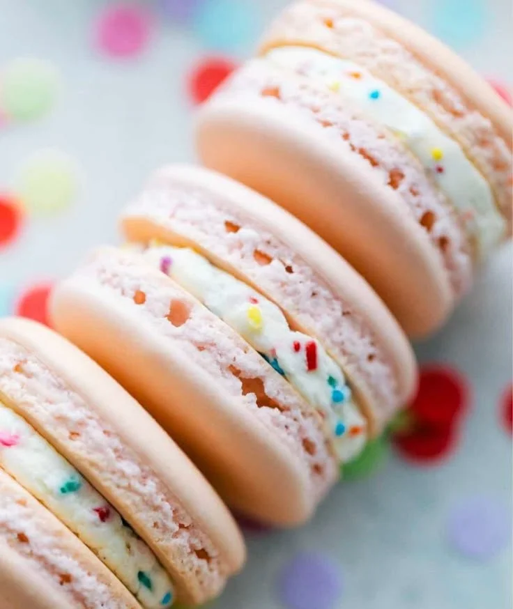 Colorful birthday cake macarons stacked on a decorative plate.