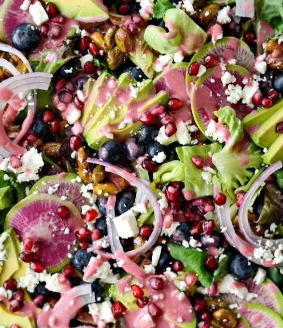 A vibrant blueberry pistachio spring salad served in a bowl with fresh greens.