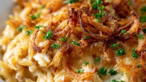 French Onion Chicken Orzo Casserole dish, topped with melted cheese and caramelized onions