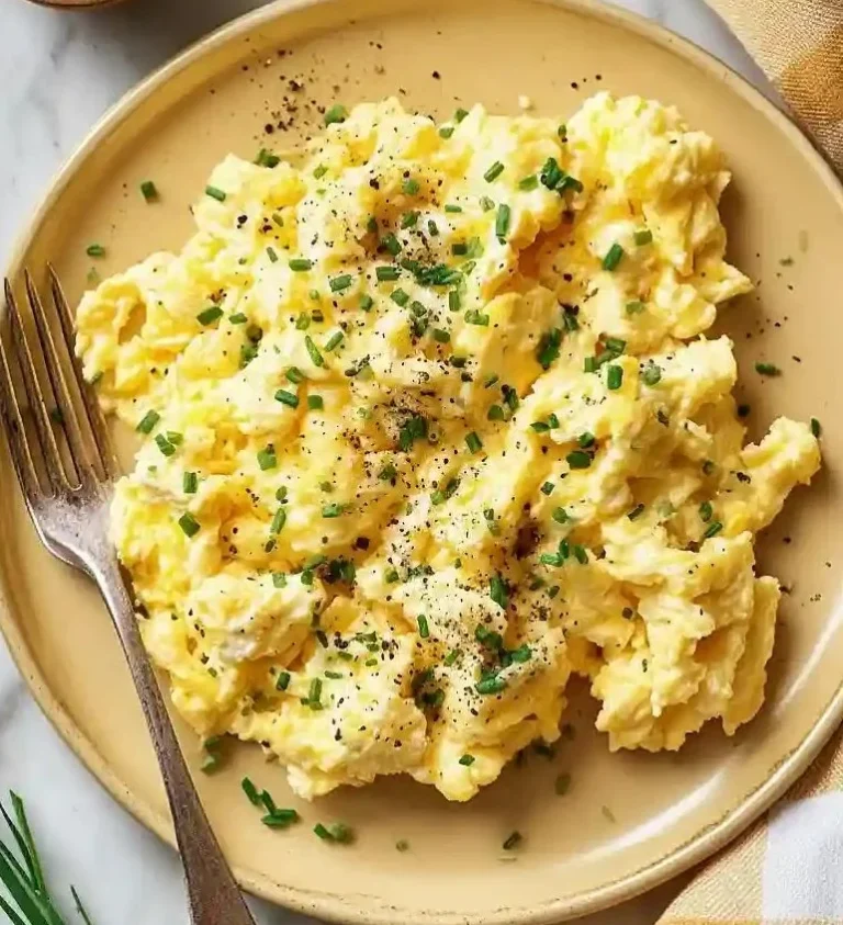 A plate of homemade cottage cheese scrambled eggs garnished with herbs.