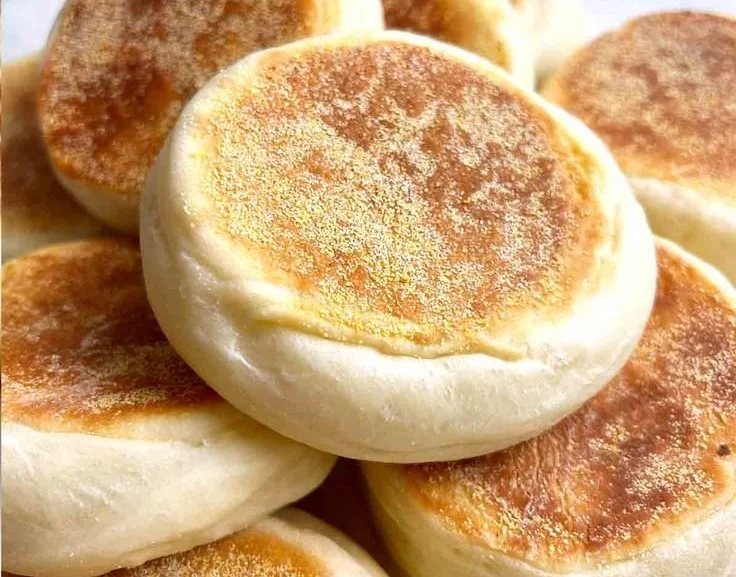 Freshly baked homemade English muffins cooling on a wire rack.
