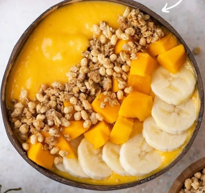 Delicious mango smoothie bowl topped with fruits and nuts