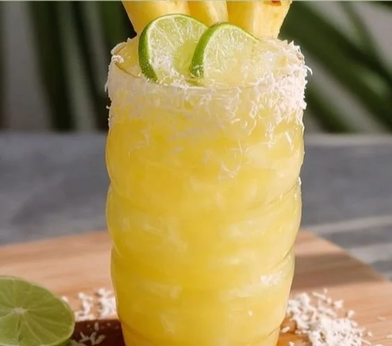 Refreshing Non Alcoholic Piña Colada Punch in a glass with fruit garnishes