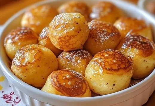 Delicious pancake poppers served on a plate with syrup and fruit