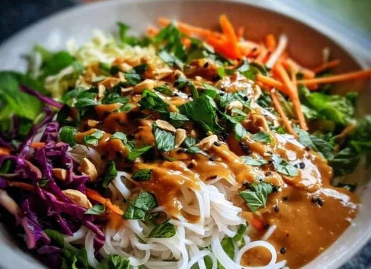 Delicious spring roll salad topped with creamy peanut dressing and fresh vegetables
