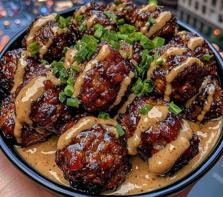 Sticky Hoisin meatballs garnished with scallion sauce on a white plate.