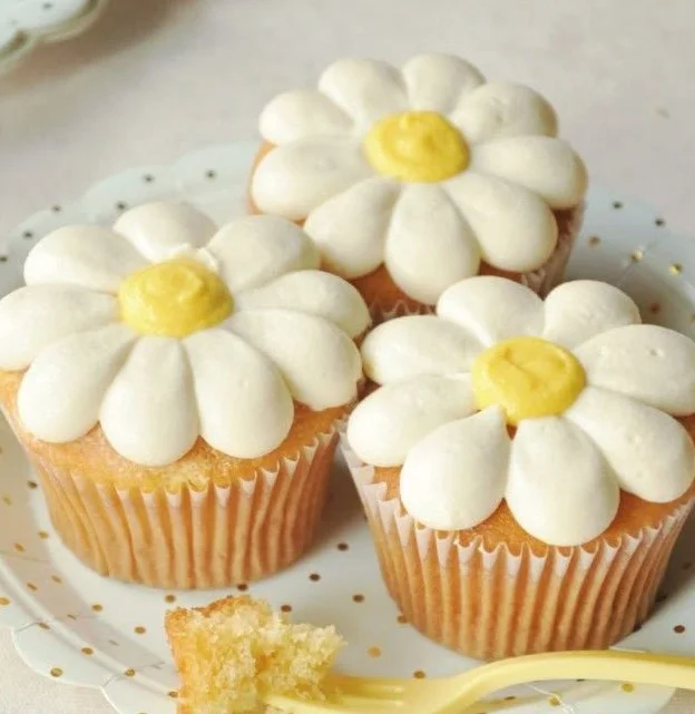 Delicious daisy cupcakes decorated with colorful icing and edible flowers.