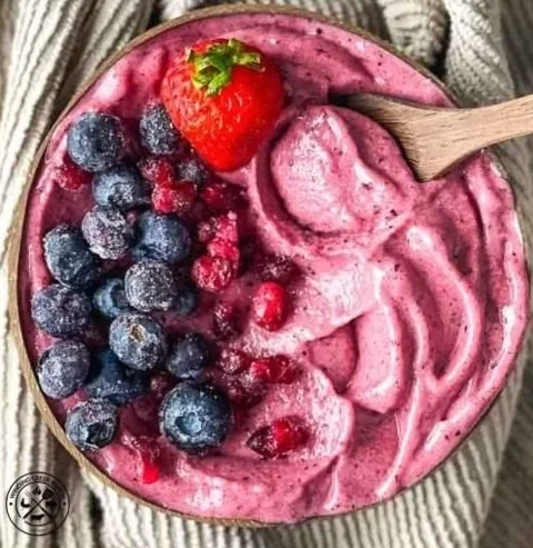 Thick and colorful smoothie bowl topped with fresh fruits and granola