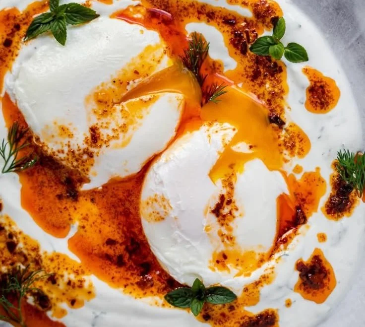 Delicious Turkish Eggs Cilbir topped with yogurt and spices, served in a bowl.