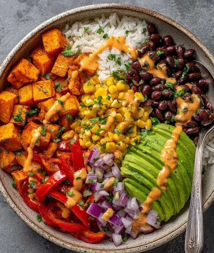 Vegan sweet potato burrito bowl with fresh vegetables and spices
