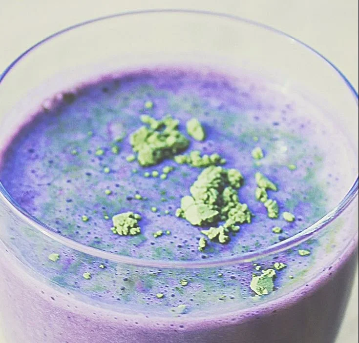 Wild blueberry vanilla matcha smoothie in a glass with fresh blueberries