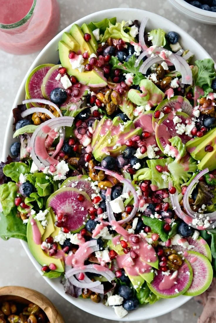 A vibrant bowl of Blueberry Pistachio Spring Salad with fresh greens, berries, and nuts
