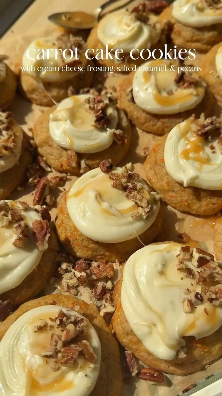 Delicious carrot cake cookies stacked on a plate, topped with cream cheese frosting.