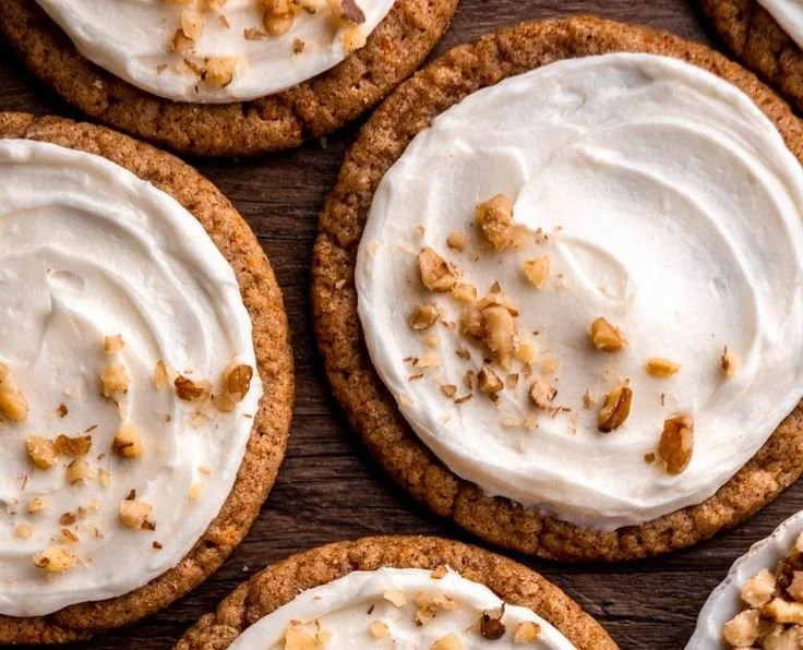 Chewy carrot cake cookies on a plate with icing and walnuts