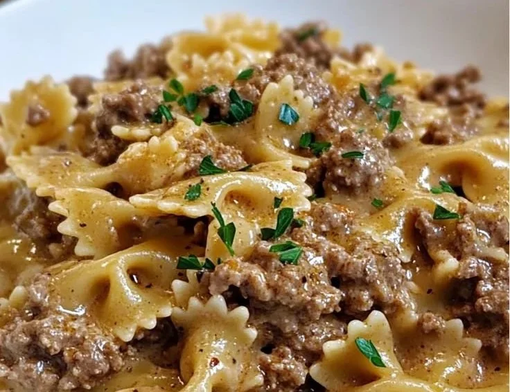 Creamy beef pasta dish with herbs and cheese, served in a bowl.