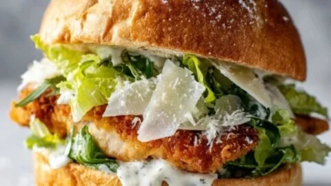 Crispy chicken caesar sandwich with fresh ingredients on a wooden plate