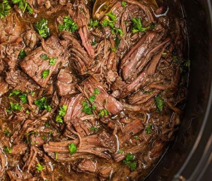 Delicious crock pot shredded beef served in a bowl with toppings.