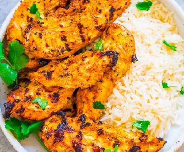 Grilled tandoori chicken garnished with herbs and spices on a plate