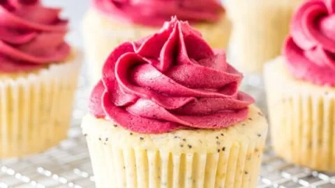 Lemon poppy seed cupcakes topped with creamy frosting on a white plate.
