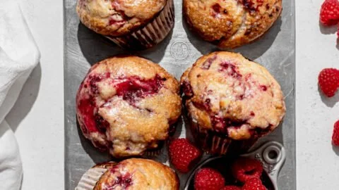 Freshly baked Lemon Raspberry Muffins with a golden top and vibrant raspberries