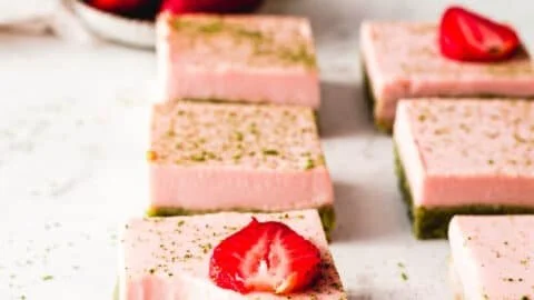 Matcha strawberry cream bars topped with fresh strawberries and a creamy layer.