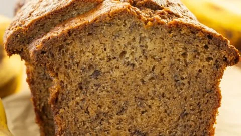 Slice of moist banana bread on a wooden cutting board