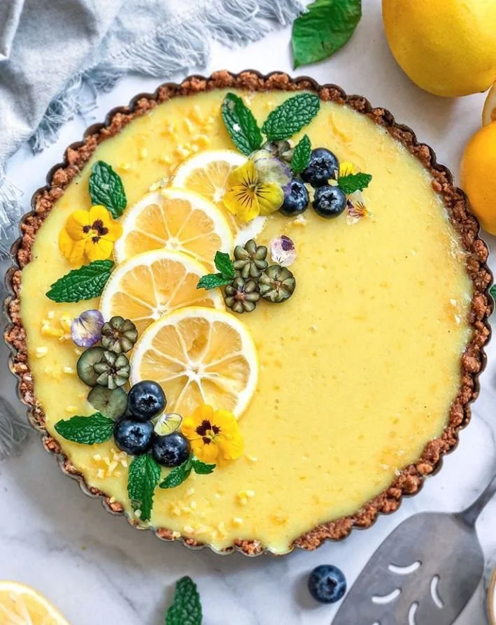 Delicious no bake vegan lemon tart topped with fresh fruit and mint leaves