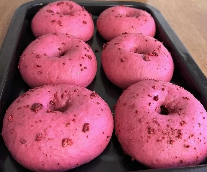 Freshly baked Raspberry Sourdough Bagels on a wooden board