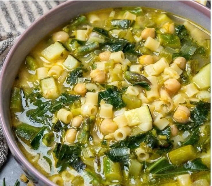 Bowl of spring minestrone soup filled with fresh vegetables and herbs