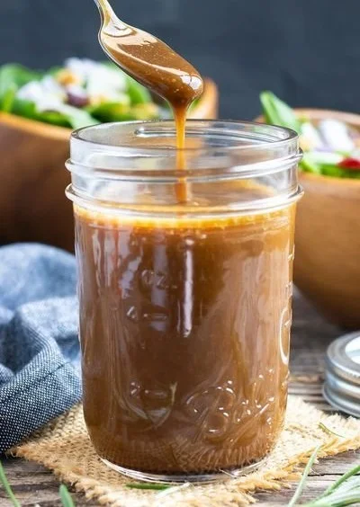 Delicious homemade balsamic vinaigrette in a glass jar with fresh ingredients.
