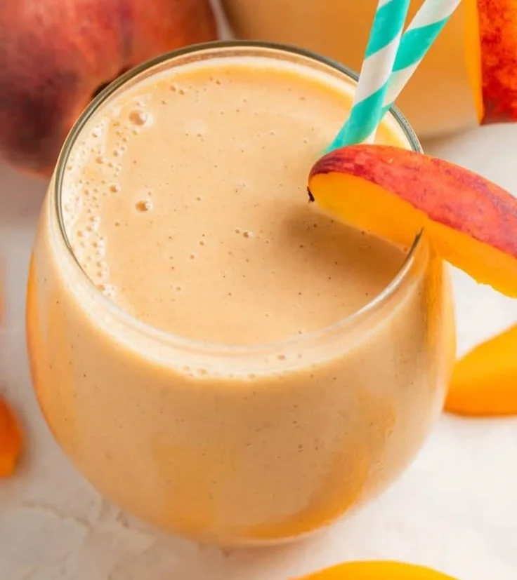 Delicious Banana Peach Smoothie in a glass topped with a slice of peach.