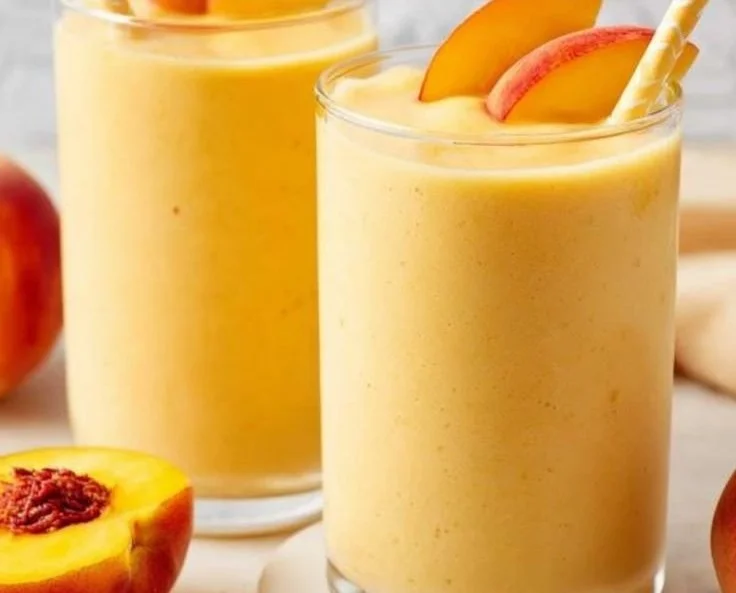 Delicious Banana Peach Smoothies in a glass with fresh fruit garnish.