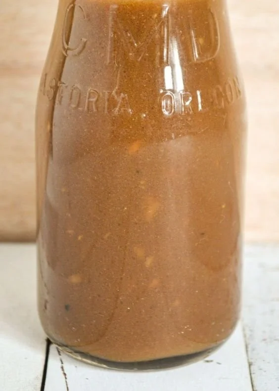 A fresh salad topped with homemade vinaigrette dressing on a wooden table.