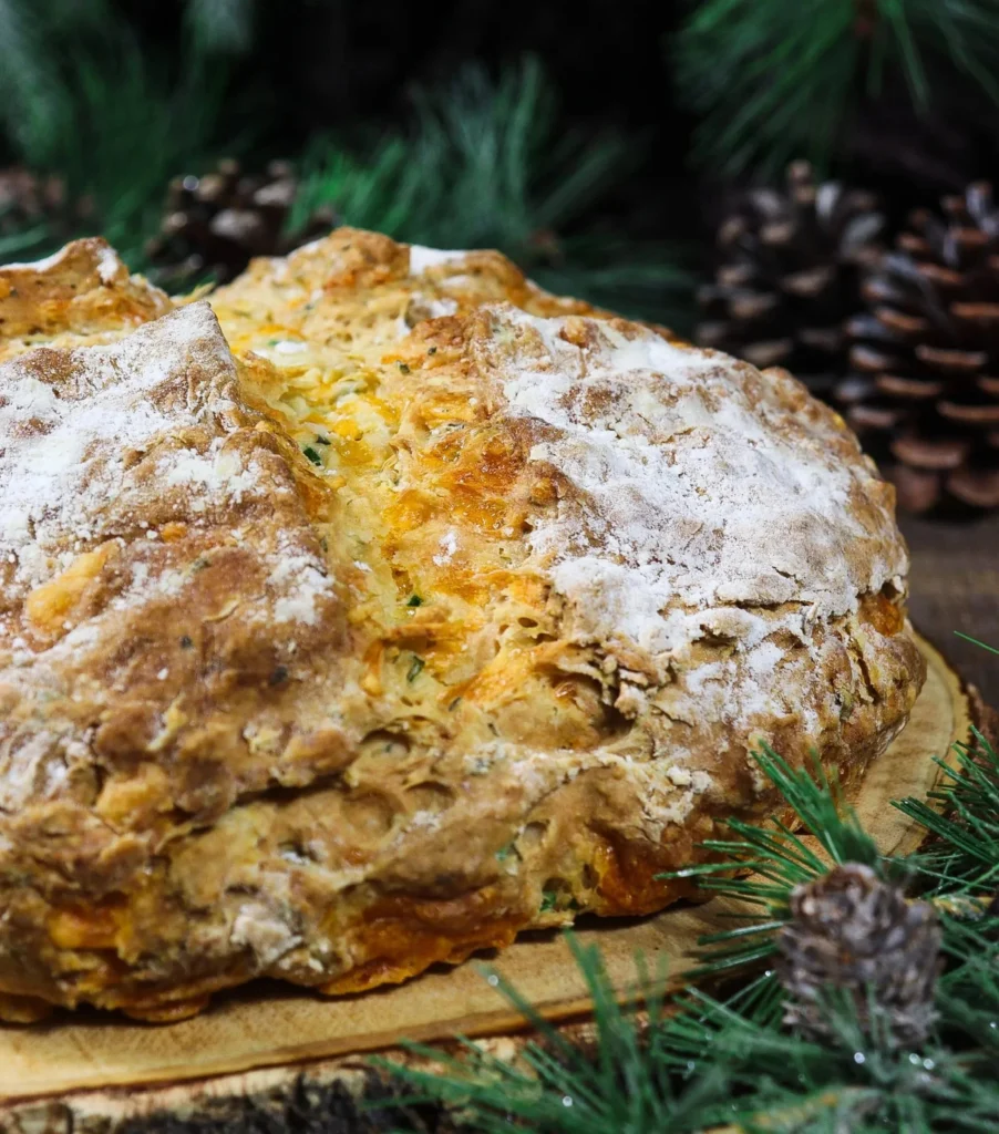 Freshly baked Cheddar and Herb Soda Bread on a wooden cutting board.