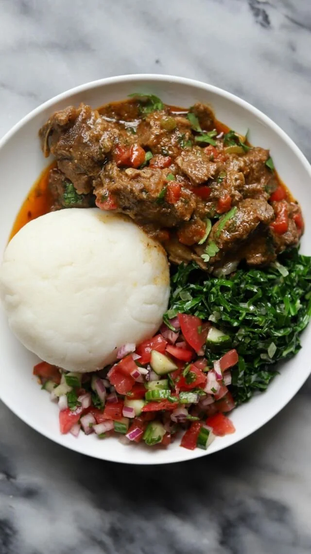 Delicious Kenyan Goat Wet Fry served with collard greens and tomato onion salad