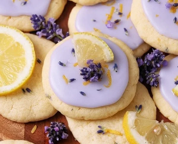 Plate of freshly baked Lemon Lavender Cookies with lemon zest and lavender flowers.