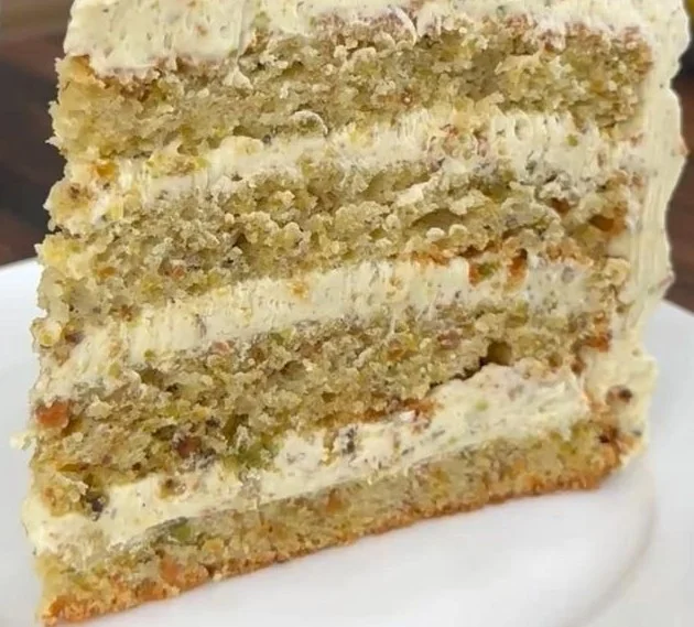Slice of pistachio cake decorated with pistachio buttercream frosting.