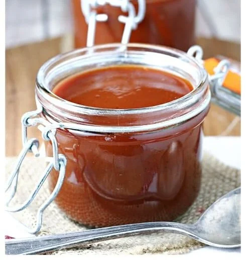 Roasted rhubarb barbecue sauce served in a bowl with barbecue brush