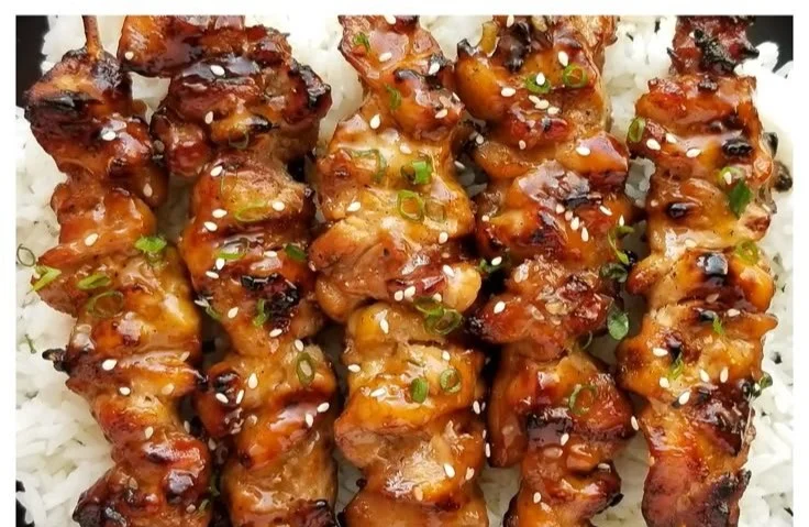 Grilled teriyaki chicken skewers garnished with sesame seeds and green onions