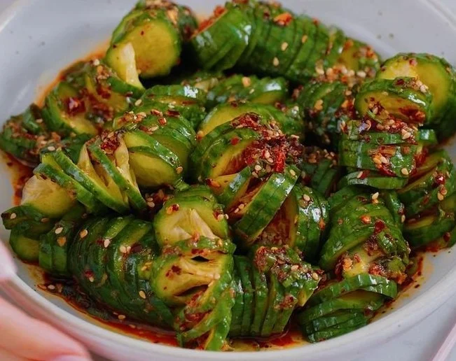 Bowl of Asian Spicy Cucumber Salad garnished with chili flakes and sesame seeds