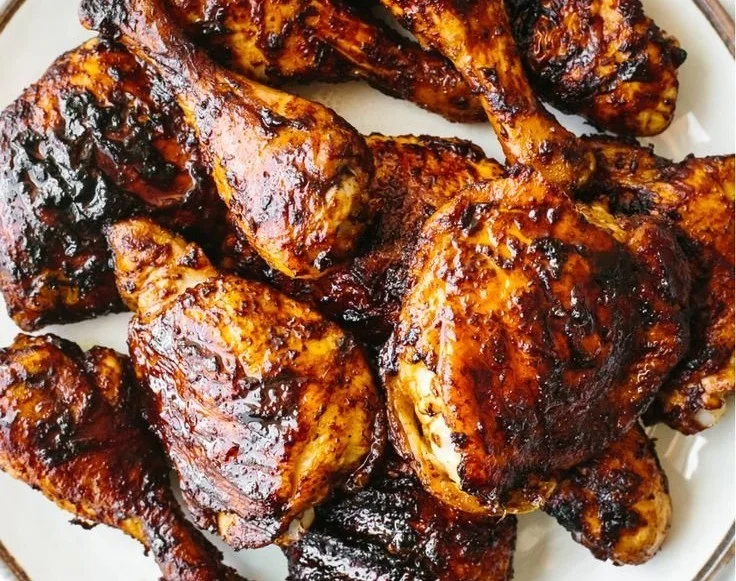 Grilled BBQ Chicken garnished with herbs on a wooden platter