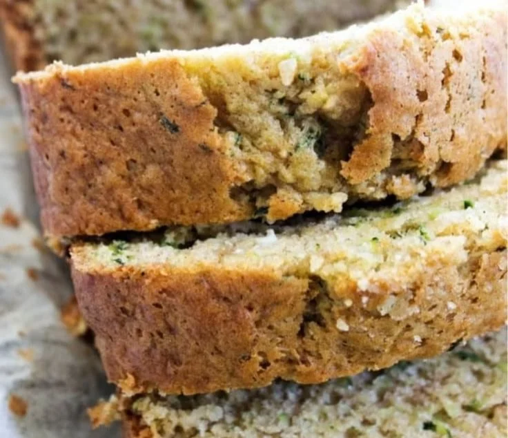 Loaf of best ever zucchini bread with slices on a wooden board.